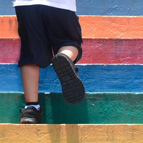 Young boy in shorts' legs running up colourful steps