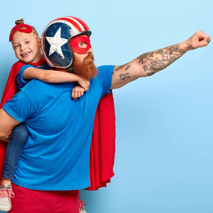man in superhero outfit with daugther on piggy back