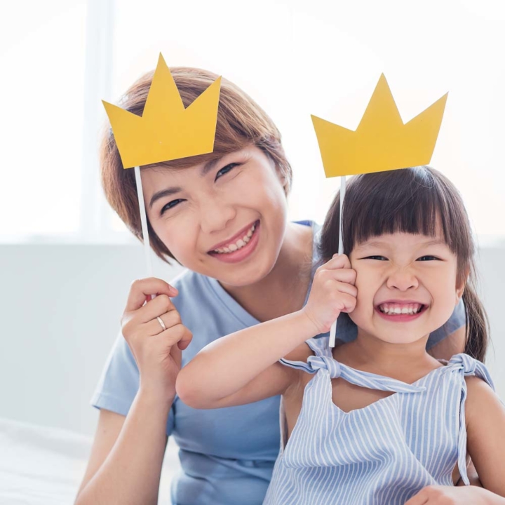 Mother and daughter holding handcrafted crowns above their head